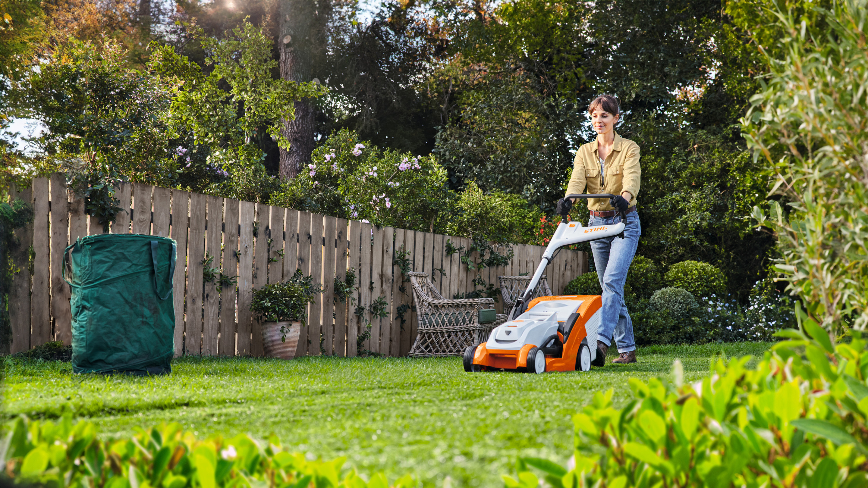 Eine Frau mäht den Rasen mit STIHL Akkurasenmäher RMA 239 C