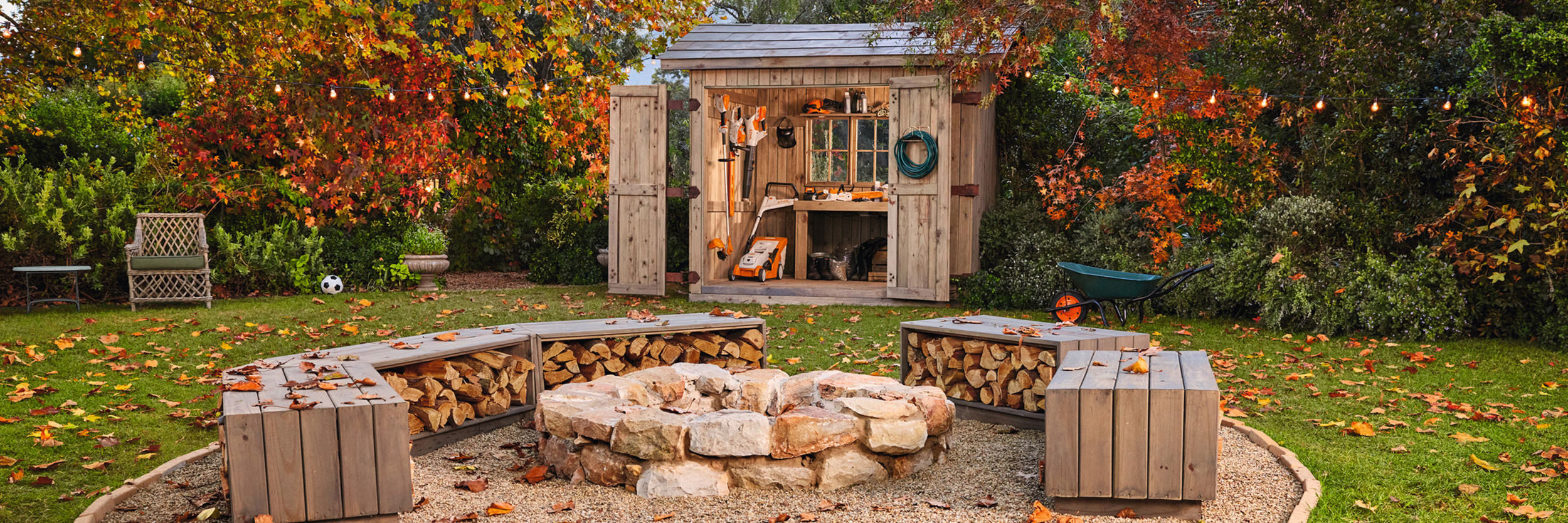 Herbstgarten mit Schuppen voller STIHL Gartengeräte und Lagerfeuerstelle