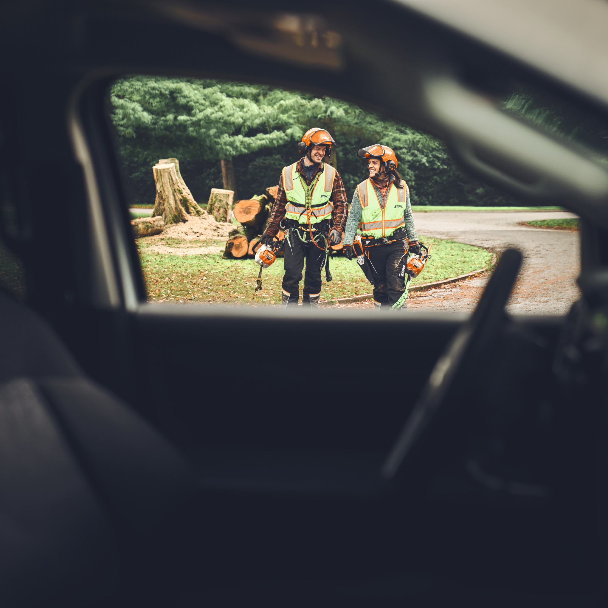 Mann und Frau auf dem Weg zum Auto mit STIHL Akku-Kettensäge MSA 190 T, MSA 220 T und Akku-Stichsäge GTA 40